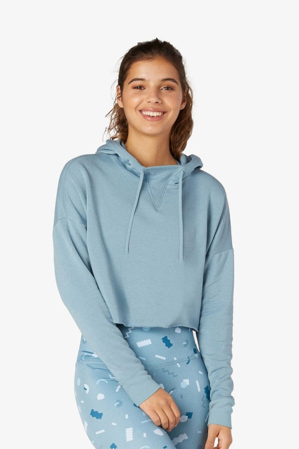Woman wearing a light blue hoodie and patterned pants on a white background