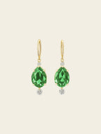 Gold earrings with green gemstones on a white background