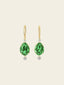 Gold earrings with green gemstones on a white background
