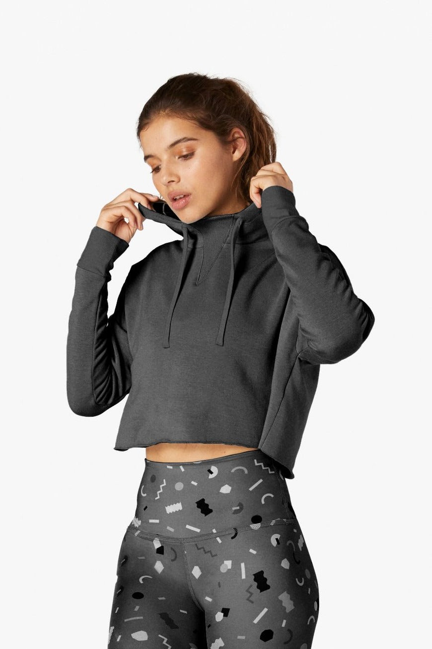 Woman wearing a dark gray hoodie with a plain background