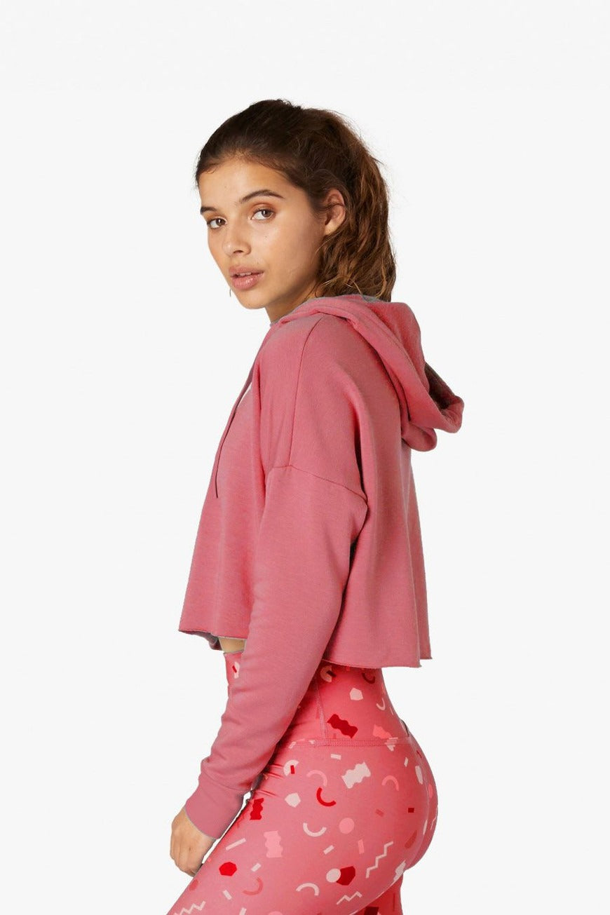 Person wearing a pink hoodie and pants with heart patterns on a white background