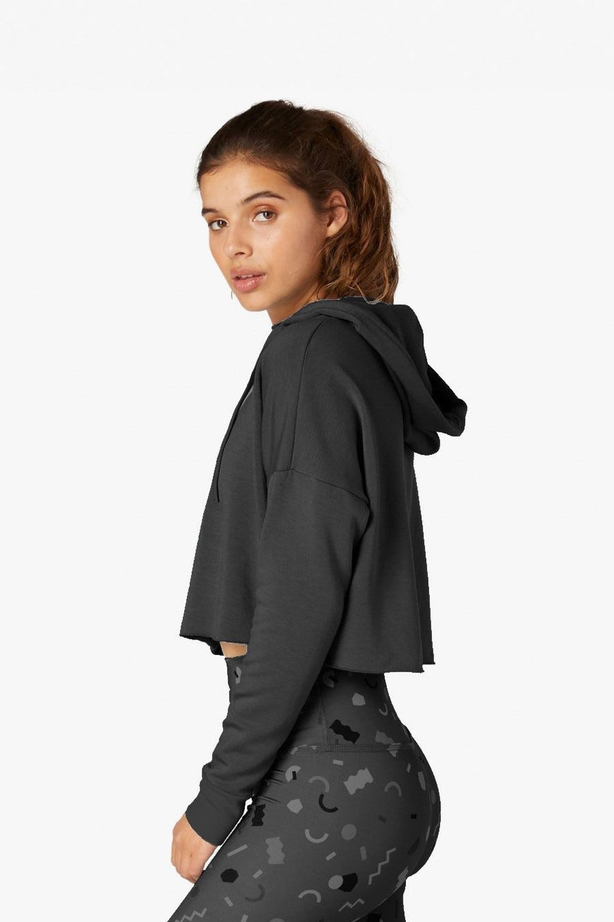 Woman wearing a dark gray hoodie with a plain background